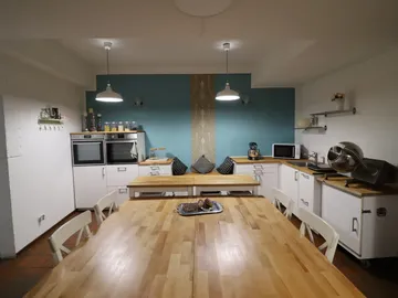 Große, moderne Küche mit Holztafel und Kochgeräten.