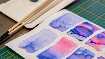 Paint samples on paper with brushes nearby.