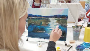 Frau malt Landschaft im Kunstunterricht.