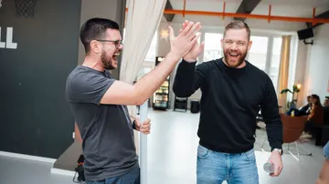 Two men high-fiving in a bright room.