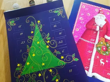 Zwei Adventskalender mit weihnachtlichen Motiven und Zahlen.