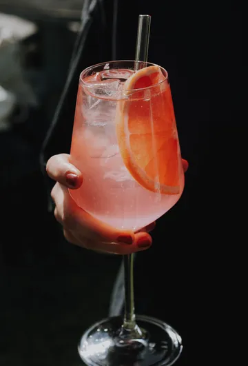 Pink drink with grapefruit slice and straw.