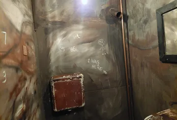 Graffitibedeckte Badezimmerwand mit Spiegel.