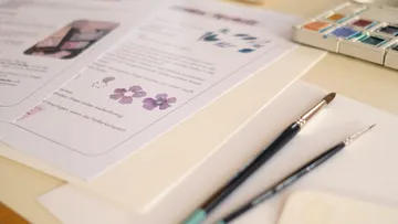 Pinsel und Papier auf künstlerischem Arbeitsplatz.