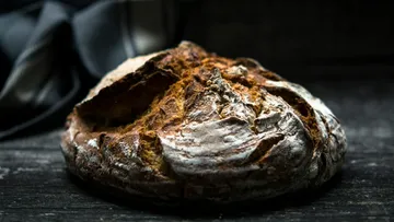 Rustikales Brotlaib auf dunklem Holztisch.