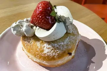 Donut with cream, strawberry on a plate.