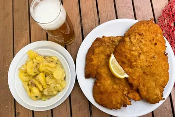 Schnitzel, potato salad, beer on wooden table.