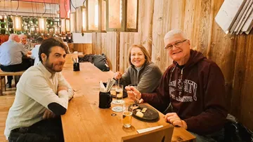 Drei Personen essen an einem Holztisch.