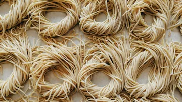 Raw pasta nests on a flat white surface.