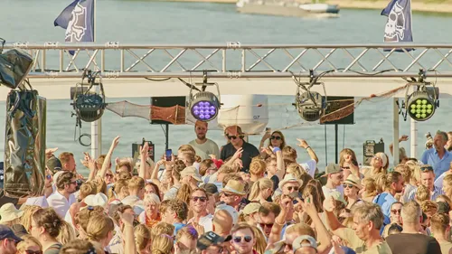 Menschenmenge tanzt auf einem Boot mit DJ.
