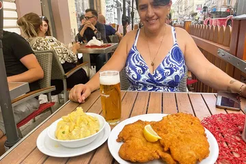 Frau isst draußen Schnitzel mit Bier.