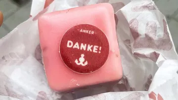 Rosa Gebäck mit 'DANKE!' Aufkleber auf Papier.