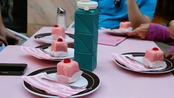 Rosa Gebäck auf Tisch mit Wasserflasche.