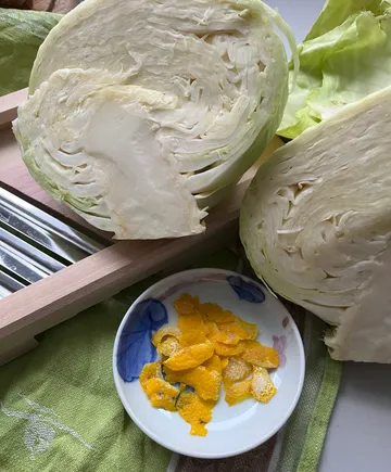 Halbierter Kohl und Orangenschalen auf einem Tisch.