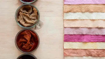 Dyed fabrics and jars on wooden table.