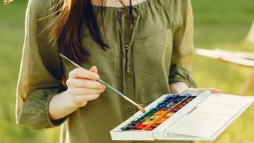 Woman mixing paint with brush outdoors.