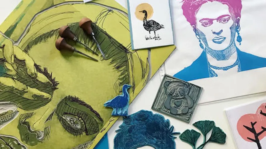 Künstlerische Drucke und Werkzeuge auf einem Tisch.