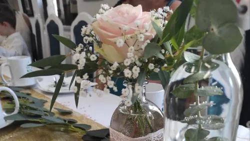 Pink rose with greenery on table.