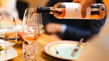 Rose wine poured into glass at dinner table.