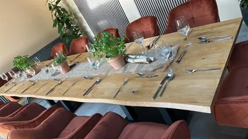 Wooden table set with chairs and plants.
