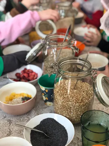 Hände bereiten Frühstück mit verschiedenen Körnern vor.
