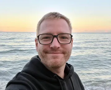 Lächelnder Mann macht Selfie am Meeres-Sonnenuntergang.