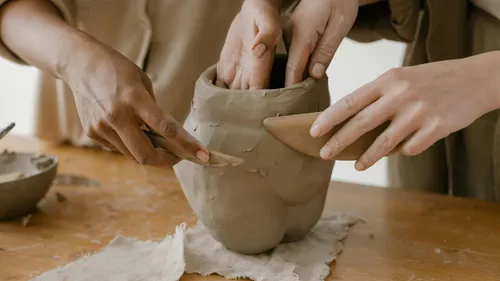 Hände formen Tonkeramik auf Tisch.