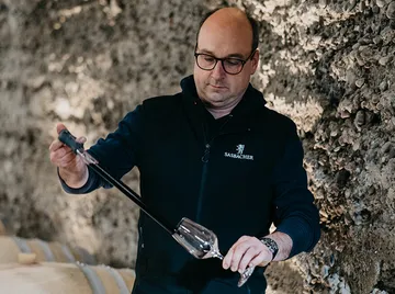 Man using pipette in wine cellar setting.