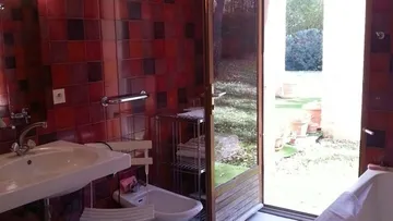 Badezimmer mit roten Fliesen, Tür zum Garten.
