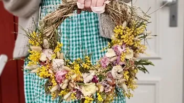Person holding a colorful dried floral wreath.