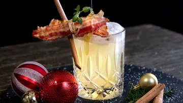 Cocktail mit Speck und Zimt, festliche Ornamente daneben.