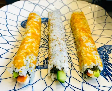 Three sushi rolls plated on a patterned dish.