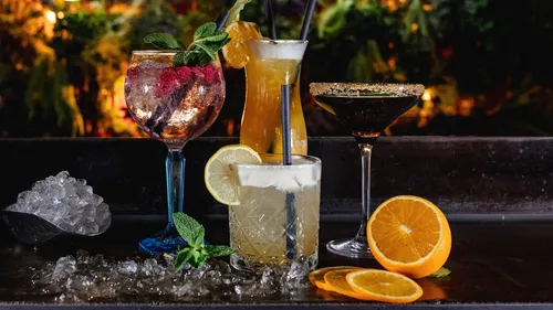 Colorful cocktails on bar with neon sign background.