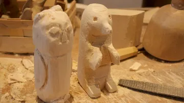Two wooden carvings on a workshop table.