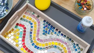 Colorful mosaic tiles in a wooden tray.
