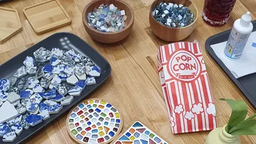Craft table with mosaic supplies and popcorn bag.
