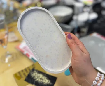 Hand holding a white capsule-shaped tray.