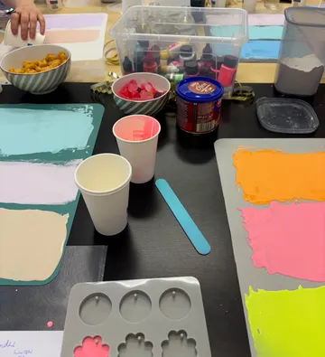 Crafting materials with paint and snacks on table.