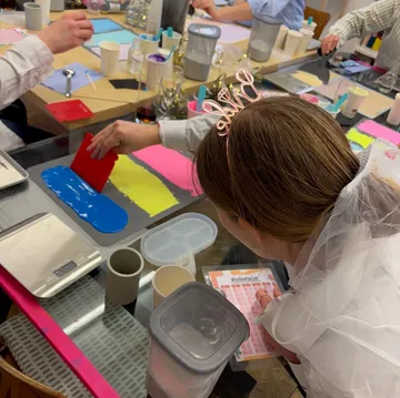 Person painting at colorful art workshop table.