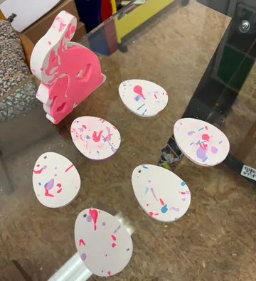 Pink rabbit and painted eggs on table.