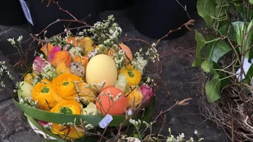Decorative basket with flowers and eggs outside.
