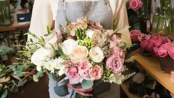 Person holding bouquet in flower shop.