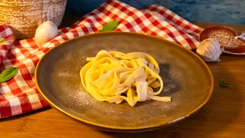 Plate of fresh pasta on wooden table.