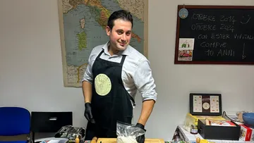 Mann in Schürze bereitet Essen im Klassenzimmer vor.