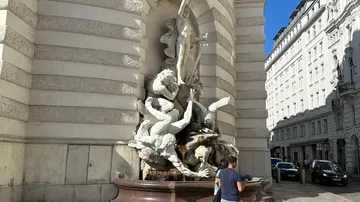 Statue group on building corner, man observing.