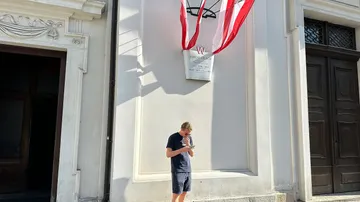 Person reading under flag at building entrance.