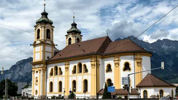 Barockkirche mit Bergen im Hintergrund.