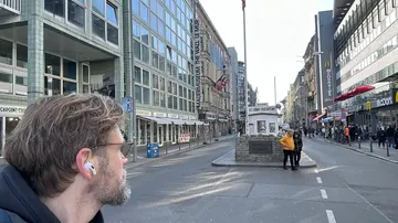 Person with earphones looks at city street.