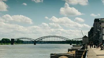 Brücke über Fluss mit Spaziergängern in der Nähe.