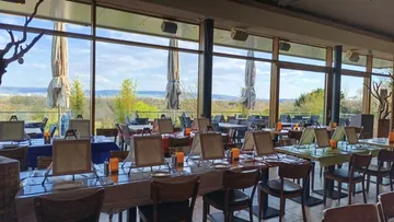 Restaurant with panoramic windows, set tables.